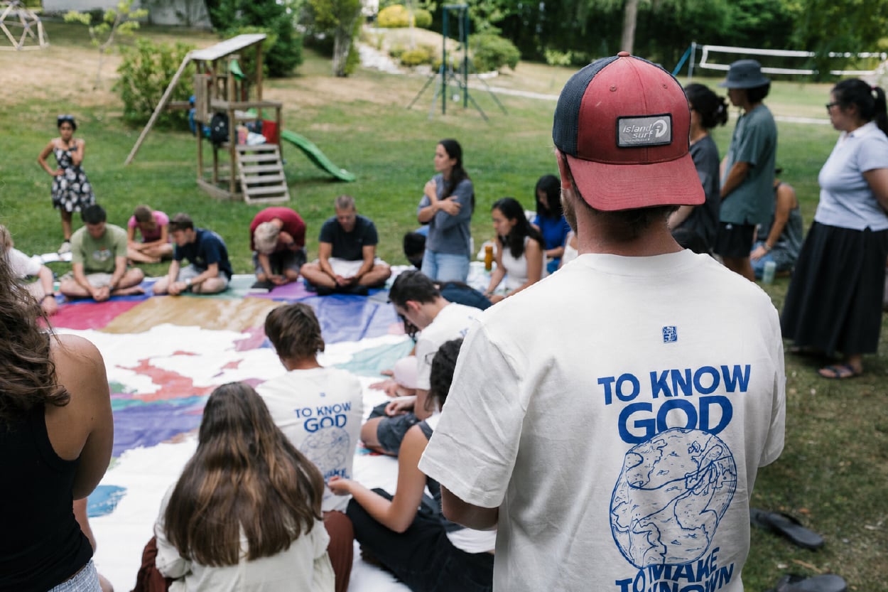 YWAM Lausanne students praying around a world map on campus